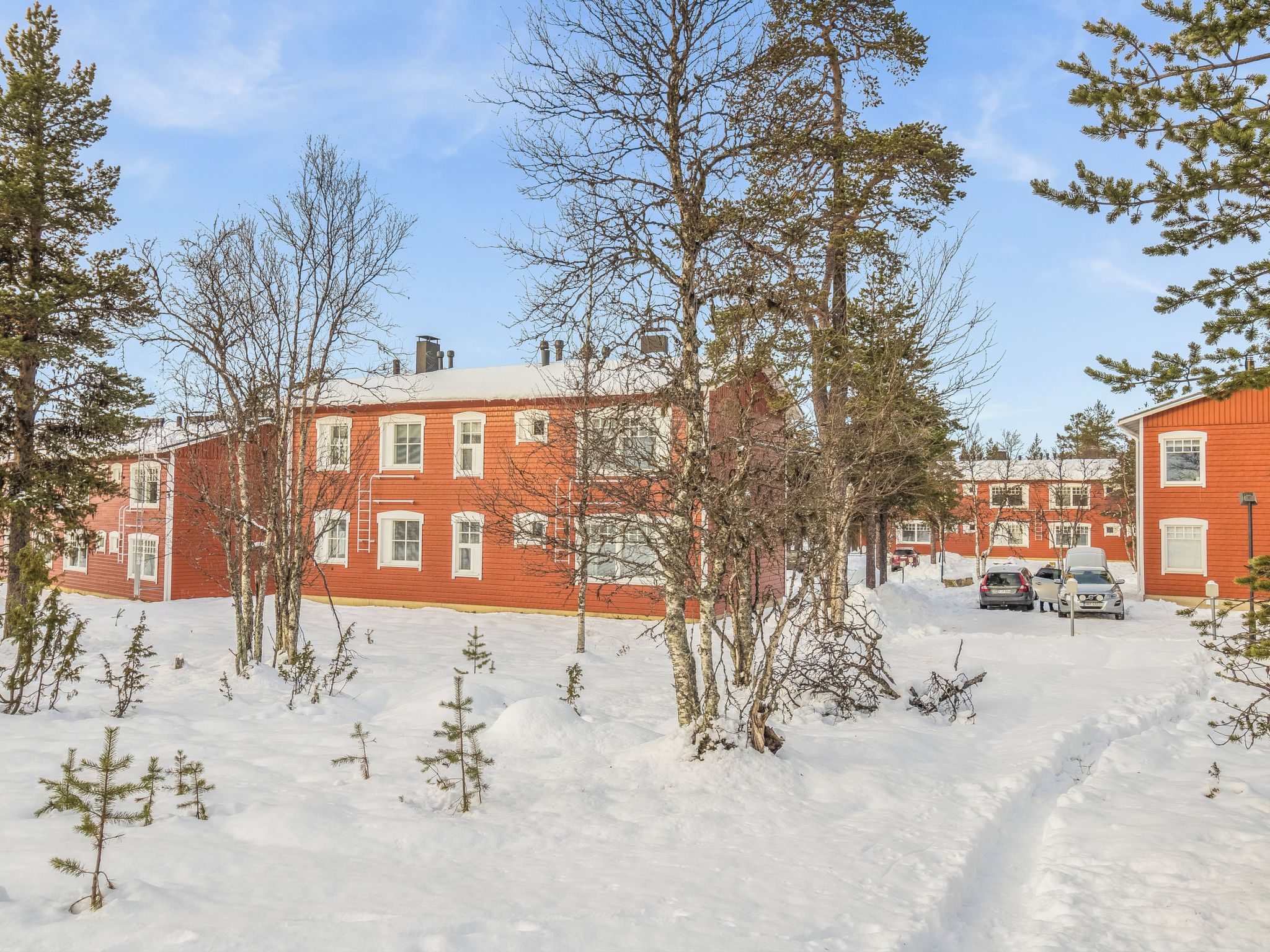 A red brick building with multiple windows and a snow-covered ground.
