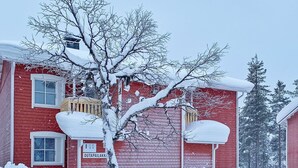 Un edificio rojo con un árbol cubierto de nieve en primer plano.