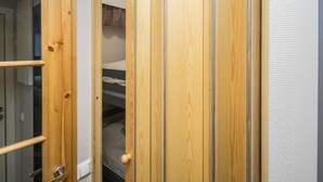 Puerta de madera con panel de vidrio y manija de metal, que da a una habitación con una cama litera y un cabecero estampado.