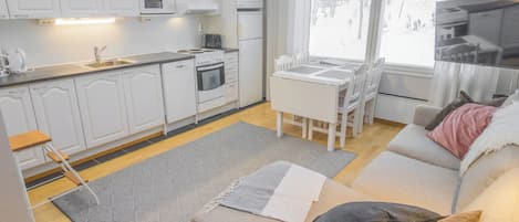 Eine moderne Küche mit weißen Schränken, einem Esstisch und einer Couch mit Kissen.