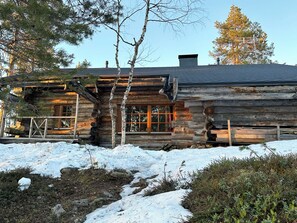 A log cabin with a chimney, windows, and a snow-covered ground. - Kiilopalkinen by Interhome (Inari)