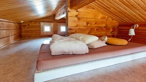 A cozy log cabin bedroom with a bed, pillows, and a small window. - Pikku-veke by Interhome (Inari)