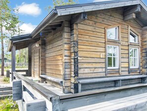 Une cabane en bois avec une véranda, une cheminée et une fenêtre.