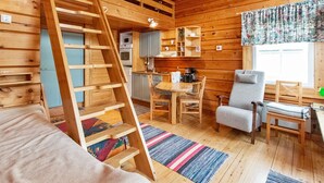 A cozy cabin interior with a wooden staircase, a dining area, a kitchen, and a window with curtains. - Pikku-veke by Interhome (Inari)