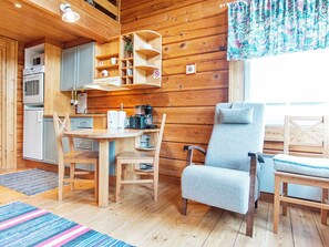 A cozy cabin interior with a dining table, chairs, a coffee machine, and a bookshelf. - Pikku-veke by Interhome (Inari)