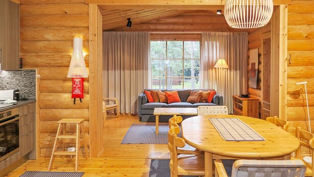 Un intérieur chaleureux de chalet en bois, avec un coin repas, un canapé et une cuisine.