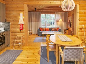 Un intérieur chaleureux de chalet en bois, avec un coin repas, un canapé et une cuisine.