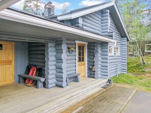 Une cabane en rondins avec un porche, un banc et une porte.