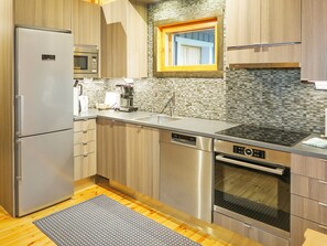 A modern kitchen with stainless steel appliances, wooden cabinets, and a tiled backsplash.