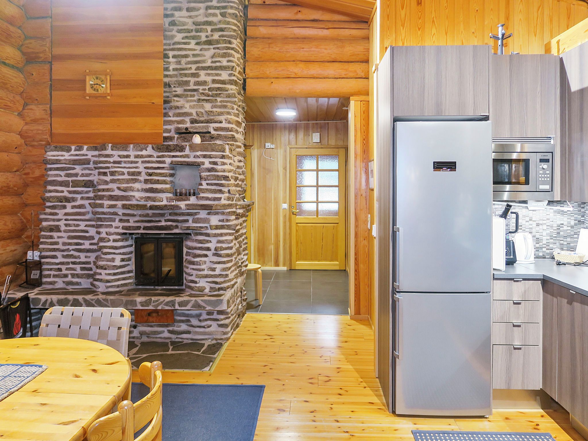 A cozy kitchen with a stone fireplace, a refrigerator, and a microwave.