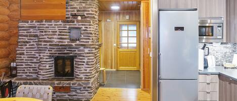 A cozy kitchen with a stone fireplace, a refrigerator, and a microwave.