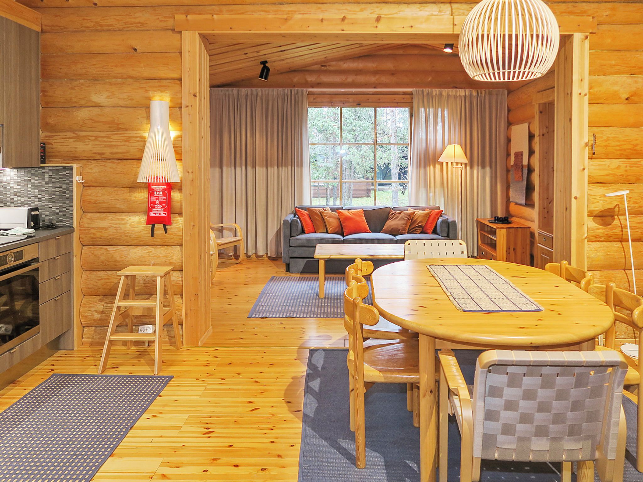 Interior acogedor de una cabaña de troncos con comedor, sofá y cocina.