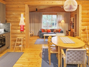 Interior acogedor de una cabaña de troncos con comedor, sofá y cocina.