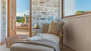 A cozy room with a stone wall, a comfortable sofa, a small table with candles, and a view of the outdoors. - Gorgeous home in Cera with WiFi (Cera)