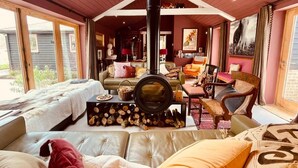 A cozy living room with a fireplace, comfortable seating, and a view of the outside. - Luxury Countryside Haven for 10 (Chichester)