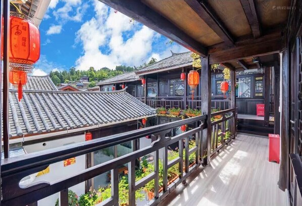 A traditional Chinese building with a balcony, red lanterns, and tiled roofs. - qingxuege (Lijiang)