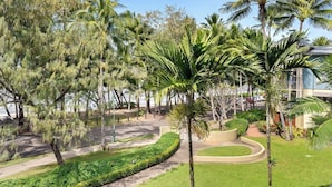 Un área ajardinada con palmeras, un camino sinuoso y un edificio al fondo.