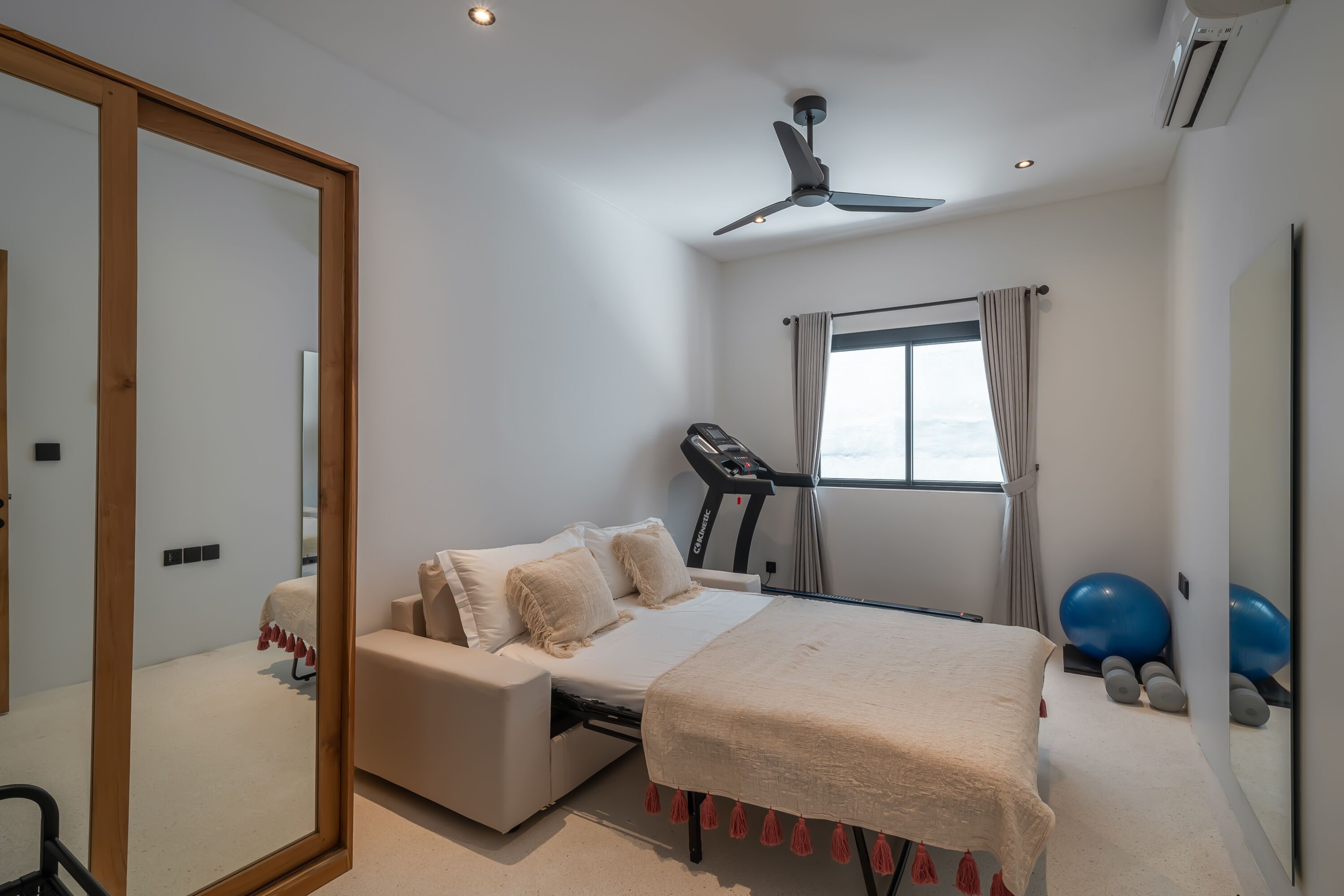 Un dormitorio con cama, una cinta de correr y pelotas de ejercicio.
