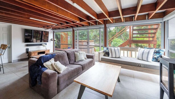 Un soggiorno moderno con soffitto in legno, un divano, un tavolino da caffè e una televisione.