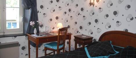 A bedroom with a bed, a desk, a chair, and a lamp.