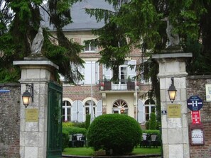 Un bâtiment historique doté d’une entrée fermée par un portail, d’une enseigne indiquant qu’il s’agit d’un hôtel et d’une autre indiquant le numéro de chambre 8.