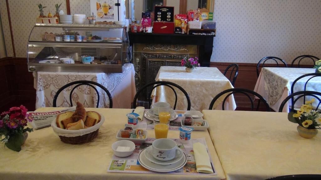 Ein Frühstücksbuffet mit Brot, Obst und Getränken in einem Essbereich mit Tischen und Stühlen.