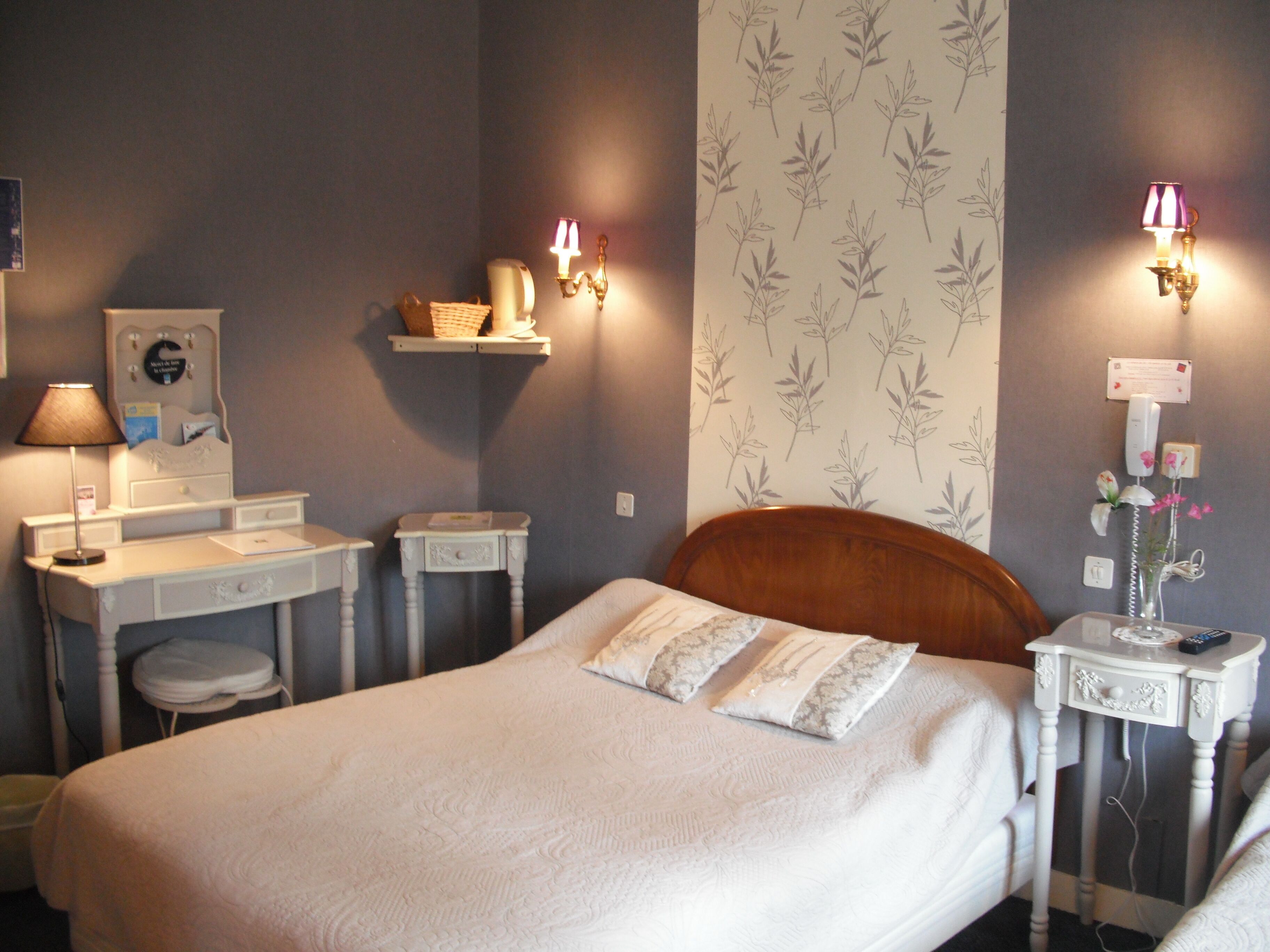 A bedroom with a bed, bedside tables, a dresser, a mirror, and wall-mounted lamps.