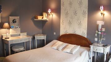 A bedroom with a bed, bedside tables, a dresser, a mirror, and wall-mounted lamps.