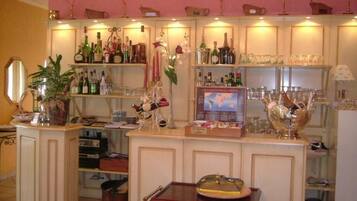 A bar area with shelves of bottles and glasses, a small table with a decorative item, and a mirror on the left.