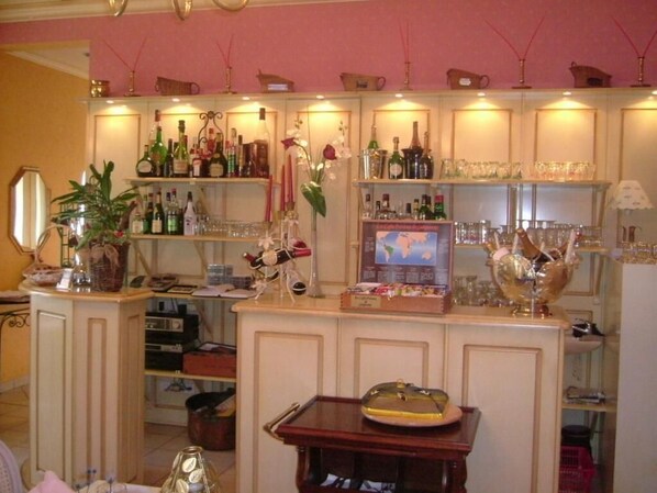 Un coin bar avec des étagères remplies de bouteilles et de verres, une petite table agrémentée d’un objet décoratif et un miroir sur le côté gauche.