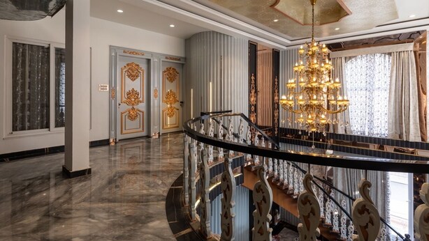A grand lobby with a marble floor, a grand chandelier, and a staircase with ornate railings.