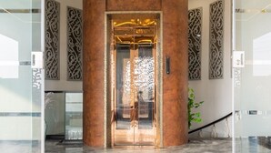 An elevator with a metallic finish, surrounded by decorative panels and a marble floor.