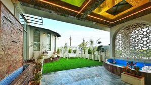 A spacious outdoor area with a green artificial turf, a marble floor, and potted plants.