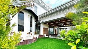 A modern building with a well-maintained lawn, outdoor seating area, and large windows.