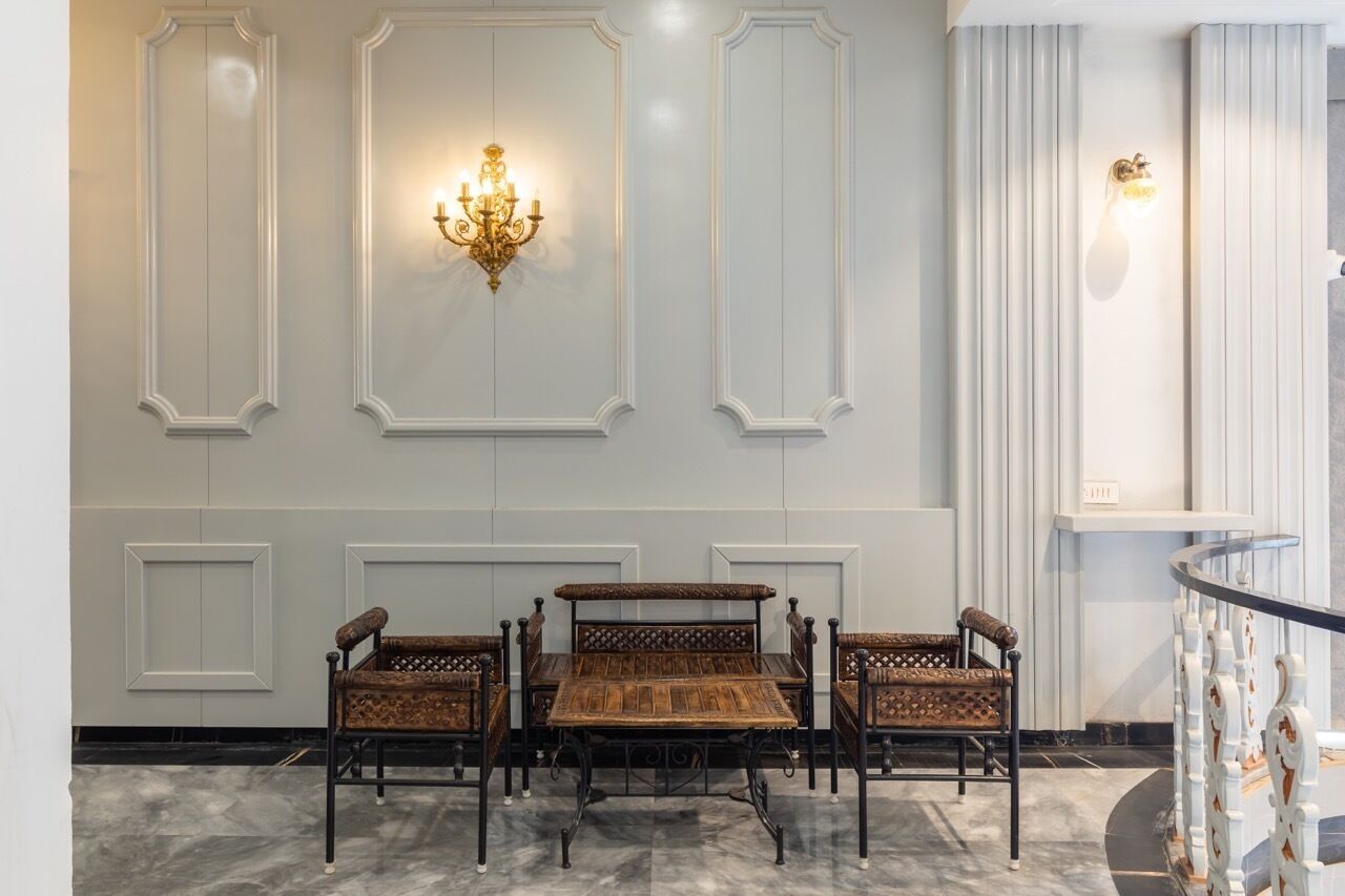 A lobby with a marble floor, a wooden bench with intricate carvings, and wall-mounted sconces.