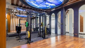 A gym with a skylight ceiling, weightlifting equipment, and a wooden floor.