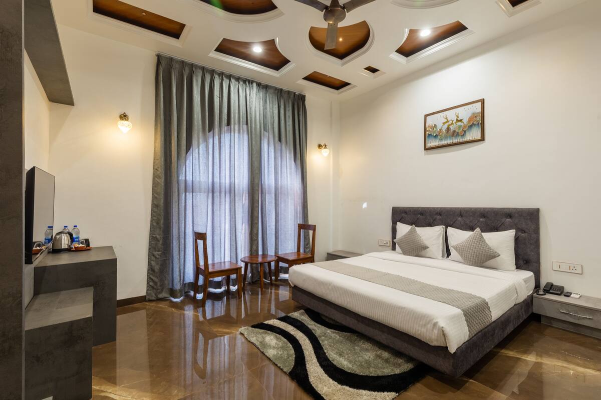 A modern hotel room with a large bed, a desk, and a chair.