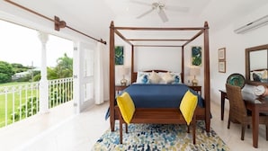 Ein Himmelbett mit Blick ins Freie, ein Deckenventilator und eine Essecke mit Stuhl und Tisch.