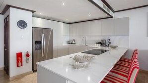 Une cuisine moderne dotée d ’un îlot central, d’appareils électroménagers en acier inoxydable et d’un banc aux rayures rouges.