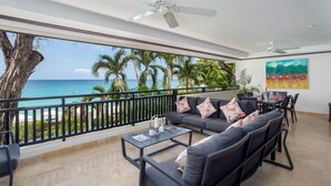 Un balcon avec vue sur l’océan, un ventilateur de plafond et un coin repas avec une table et des chaises.