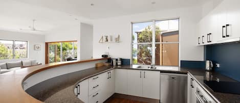 A modern kitchen with a curved countertop, built-in dishwasher, and a large window providing natural light.