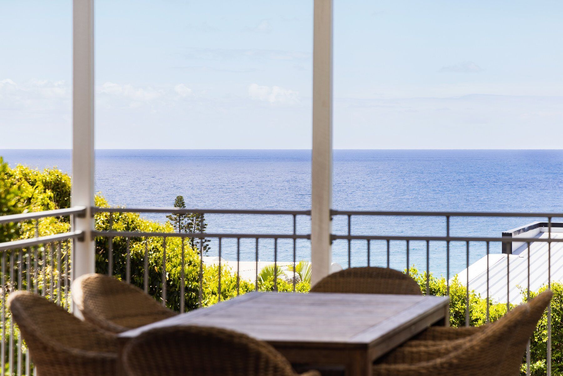 A balcony with wicker furniture and a view of the sea.