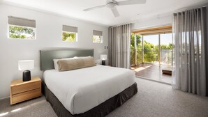 A bedroom with a bed, nightstands, a ceiling fan, and a view of a balcony.