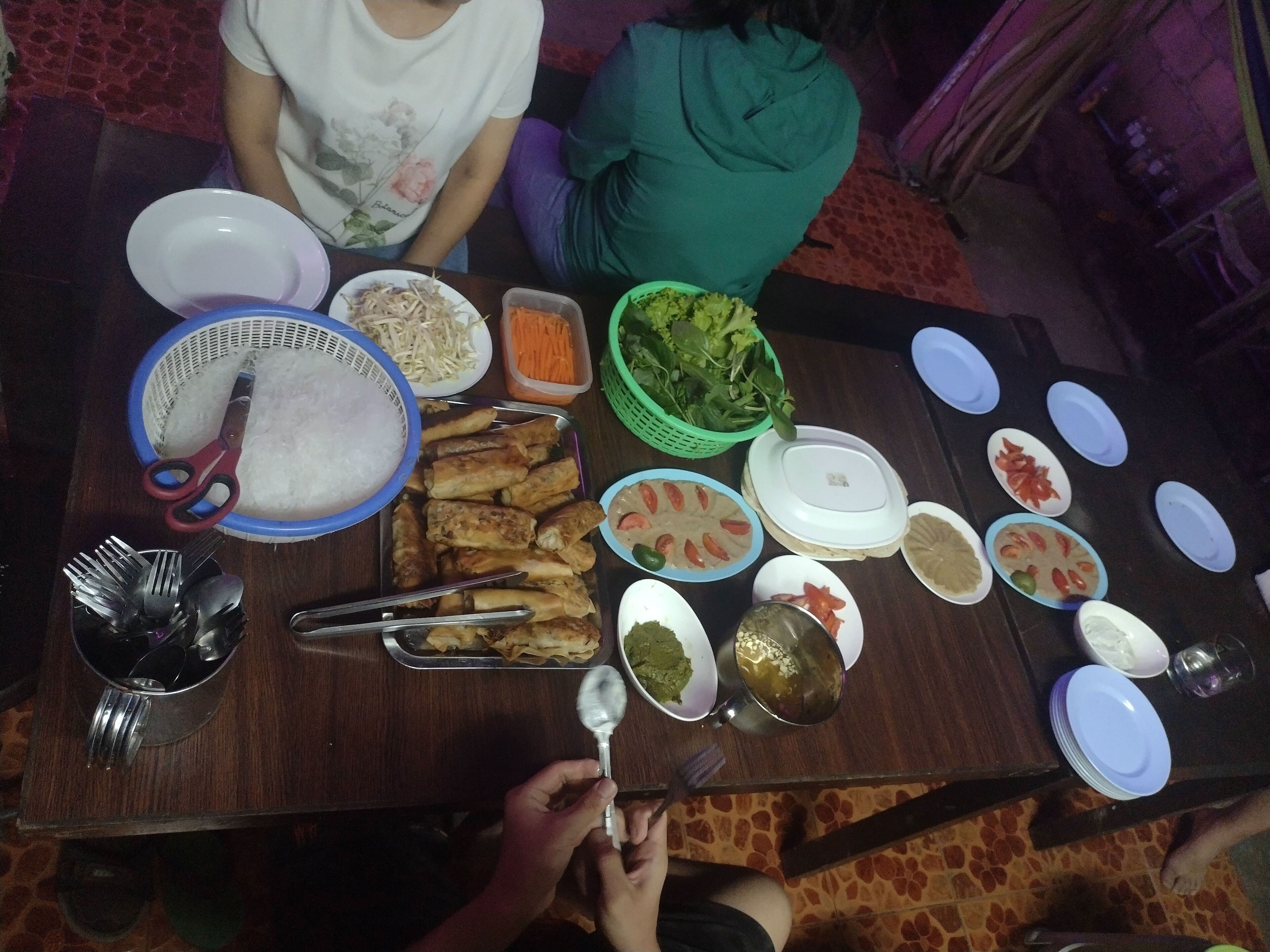 A dining table with various dishes, utensils, and a person seated at the table.