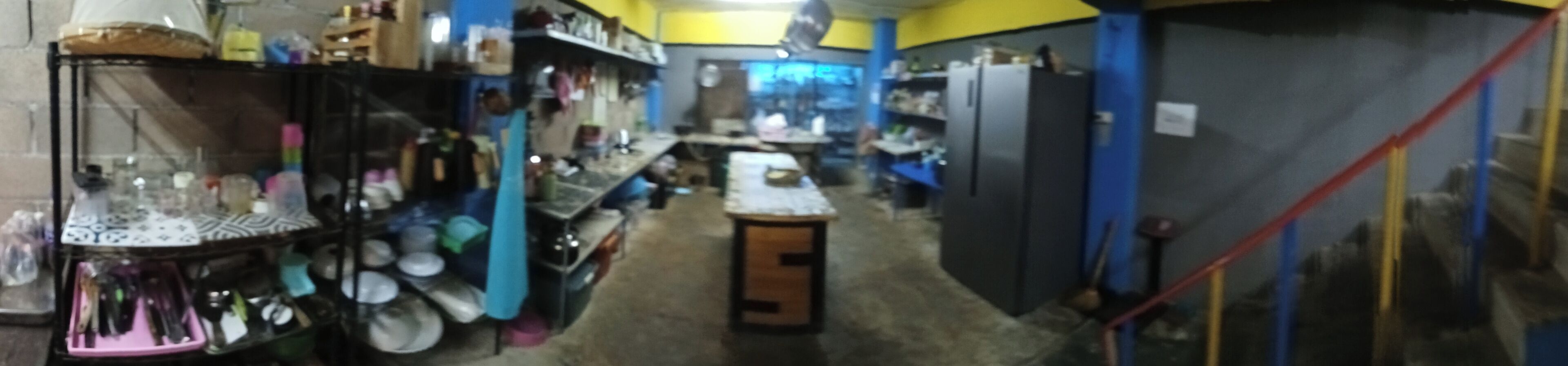A narrow corridor with shelves on both sides, leading to a central area with a table and chairs.