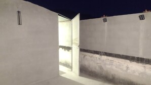 Un pasillo con una pared blanca y una puerta que da a una habitación iluminada.