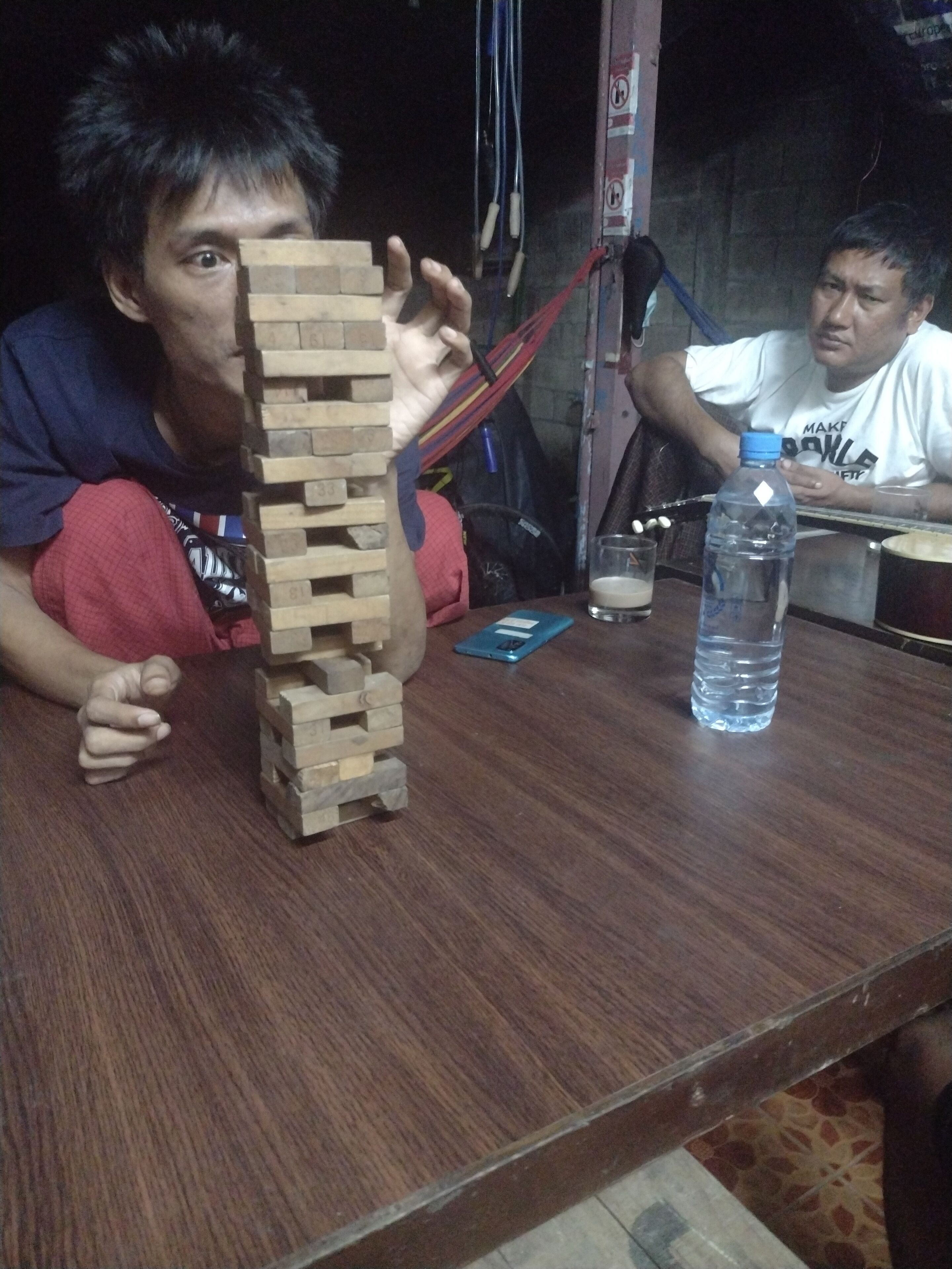 A wooden block tower on a table, a water bottle, and a smartphone.