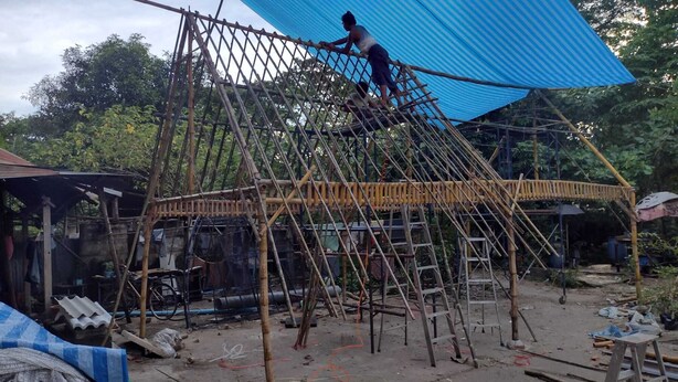 Un sitio de construcción con estructura de bambú y un lona azul cubriendo la parte superior.