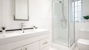 Une salle de bain moderne avec un lavabo blanc, un miroir et une douche à parois de verre.