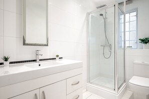 Bathroom features a white vanity, sink, and glass-enclosed shower area.